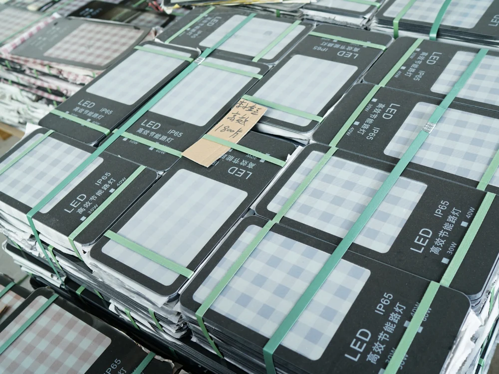 Stack of LED flood light modules with tempered-glass front covers, each module IP65-sealed before final assembly
