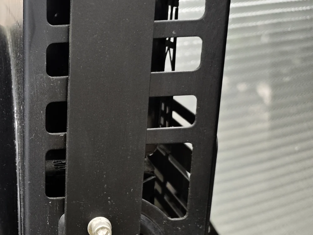 Black perforated adjustable yoke bracket of an LED high bay light, the slotted mount that locks the fixture aiming angle