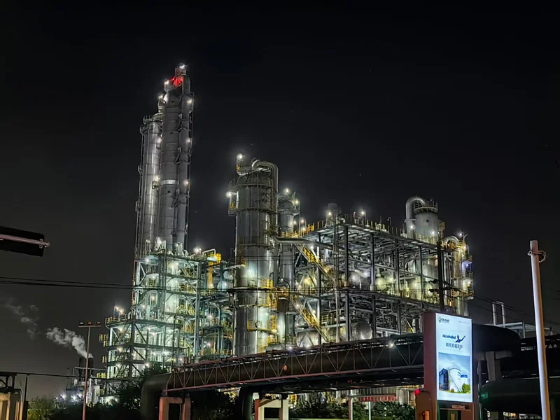 Petrochemical refinery lit at night, with distillation columns and pipe racks picked out by explosion-proof and industrial LED lighting